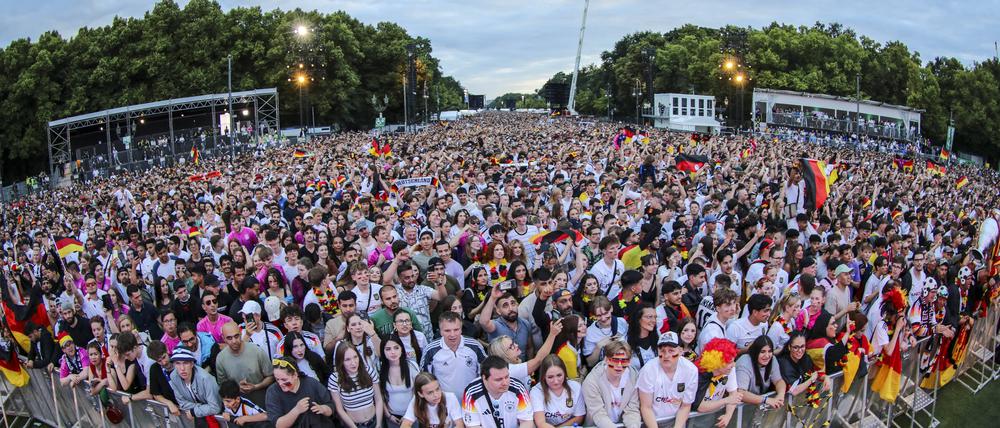 EM 2024: Public viewing in Berlin Deutschland gegen Schweiz in der Fan Zone vor dem Brandenburger Tor. Die Fans feuern ausgelassen die Mannschaft an und halten einen Pokal in die Höhe.