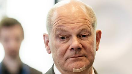Ein nachdenklich blickender Kanzler Olaf Scholz (SPD) mit einem Pflaster am Kinn nach einem Rasierunfall. 