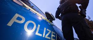 Eine Polizistin steht neben einem Polizeifahrzeug.