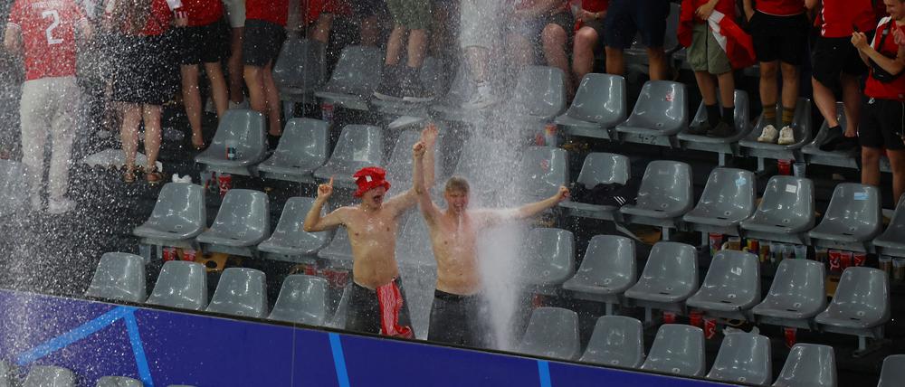 Die dänischen Fans werden auf der Tribüne vom Regen überrascht.