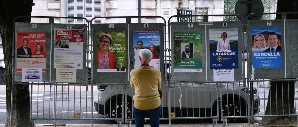 Eine Frau betrachtet Wahlplakate neben einem Wahllokal während der ersten Runde der Parlamentswahlen in Pau im Südwesten Frankreichs. 