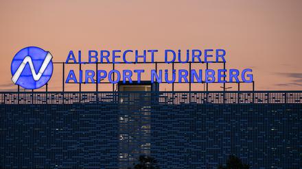 Der Schriftzug «Albrecht Dürer Airport Nürnberg» leuchtet auf dem Dach eines Parkhauses am Flughafen am Abend.