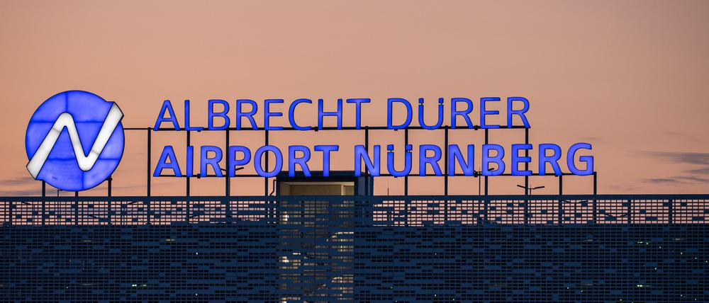 Der Schriftzug «Albrecht Dürer Airport Nürnberg» leuchtet auf dem Dach eines Parkhauses am Flughafen am Abend.