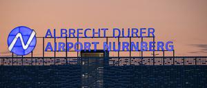 Der Schriftzug «Albrecht Dürer Airport Nürnberg» leuchtet auf dem Dach eines Parkhauses am Flughafen am Abend.