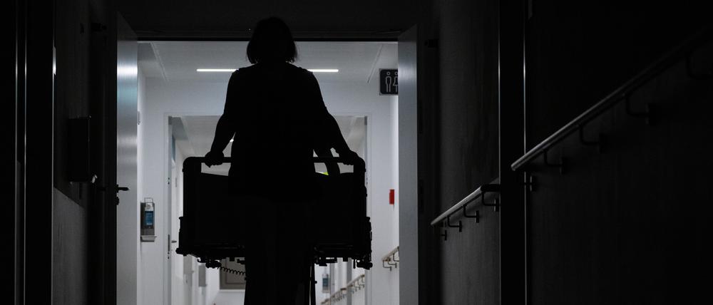 Eine Pflegerin schiebt ein Krankenbett durch den Gang einer Klinikstation.
