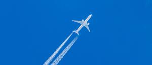Kondensstreifen und ein Flugzeug am blauen Himmel. 