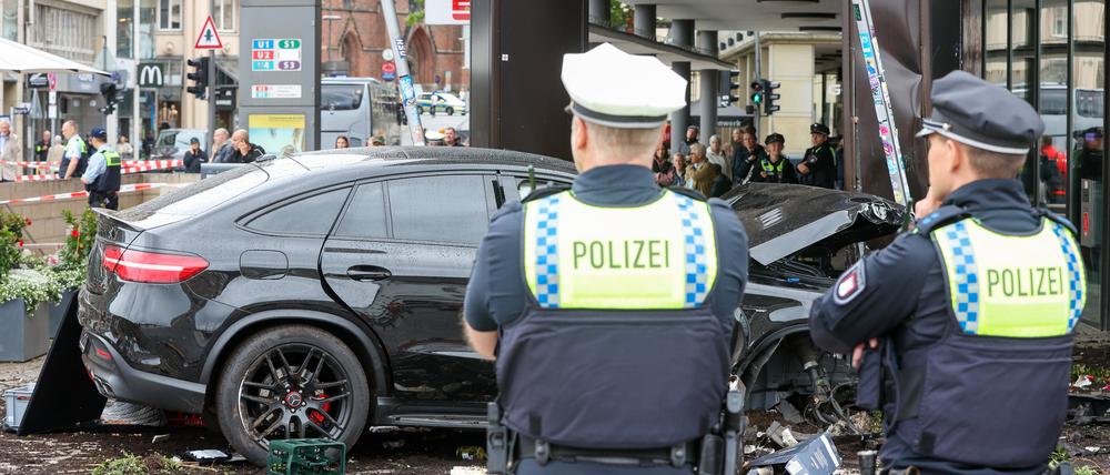 Polizisten stehen an einem demolierten Auto vor einer Sparkasse in der Hamburger Innenstadt.