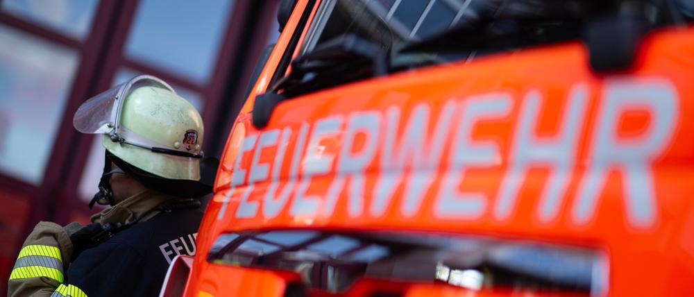 Eine Einsatzkraft der Feuerwehr steht neben einem Einsatzfahrzeug der Feuerwehr.