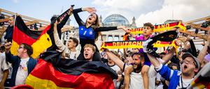 Deutschland-Fans feiern beim Public Viewing in der Fanzone am Reichstagsgebäude mit schwarz-rot-goldenen Schals und Flaggen.