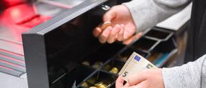 Eine Kassiererin nimmt Wechselgeld aus der Kasse eines Supermarktes (Symbolbild).