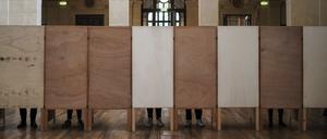 Wähler stehen in einem Wahllokal in Zentralfrankreich in den Wahlkabinen (Symbolbild).