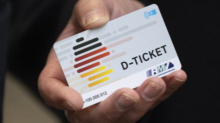 Eine Hand hält ein Deutschlandticket (Symbolbild).