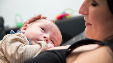 Eine Frau liegt auf einer Couch und hält ein Baby auf ihrer Brust.