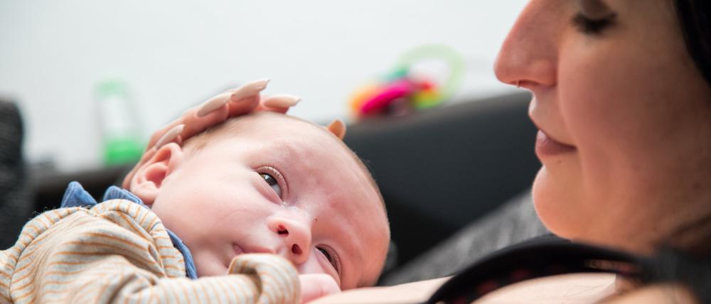 Eine Frau liegt auf einer Couch und hält ein Baby auf ihrer Brust.