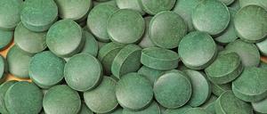 Ein Haufen kleiner grüner Tabletten aus gepresstem Spirulina-Pulver.