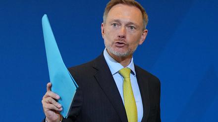 Christian Lindner (FDP), Bundesminister der Finanzen, winkt nach der Pressekonferenz zum Ergebnis der Steuerschätzung mit einem blauen Hefter.
