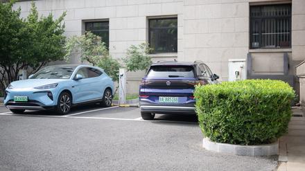 Ein chinesisches E-Auto des Herstellers Denza (l) steht neben einem deutschen E-Auto ID.6 von Volkswagen an einer Ladestation. 