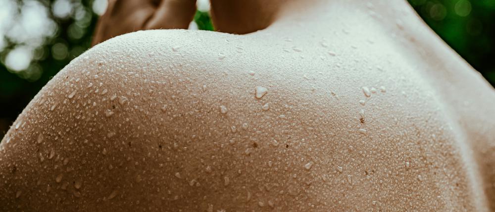 Schweißperlen rinnen vom Rücken eines Mannes.