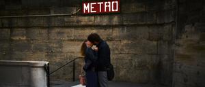 Ein Pärchen küsst sich vor einem Eingang der Pariser Metro.