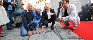 Regisseur Andreas Dresen, der Schauspieler und Autor Sebastian Stielke, Potsdams Oberbürgermeister Mike Schubert und der Filmwissenschaftler Chris Wahl hocken vor einer Platte mit dem Titel „Halt auf freier Strecke“ bei der Eröffnung des „Boulevard des Films“ (von links).