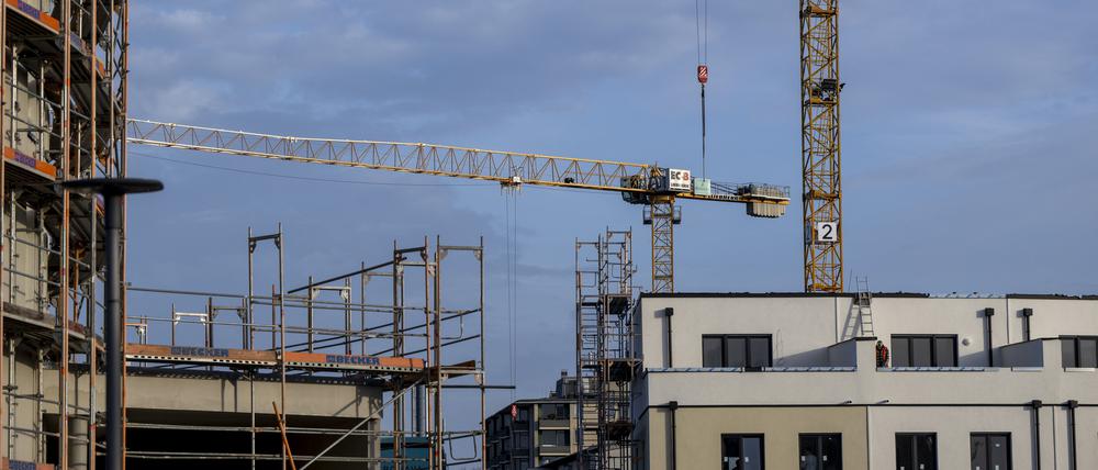 Ein Baugerüst steht an der Fassade eines noch unfertigen Wohnhauses.