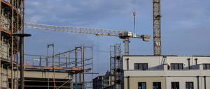 Ein Baugerüst steht an der Fassade eines noch unfertigen Wohnhauses.
