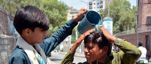 Ein Junge wäscht sich den Kopf, um sich an einem heißen Sommertag in Pakistan abzukühlen (Symbolbild).