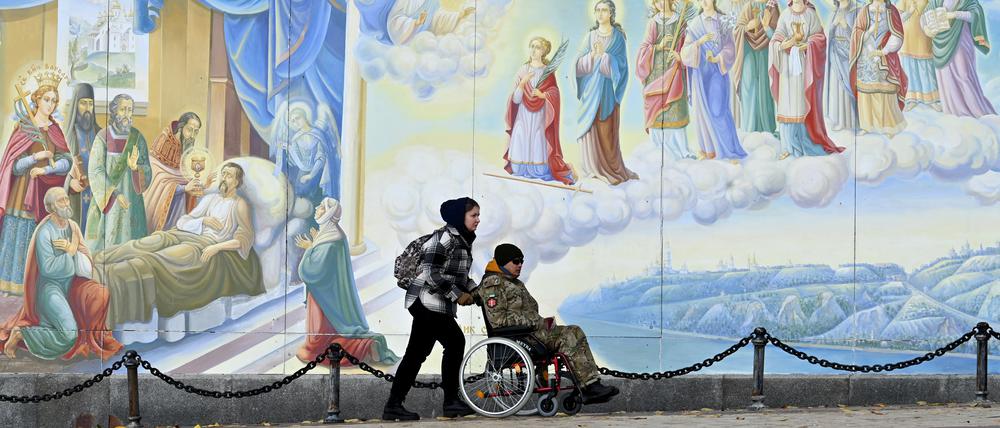 Eine Frau fährt einen Mann in einem Rollstuhl umher (Symbolfoto).