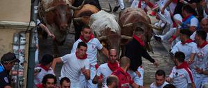 Teilnehmende laufen mit den Stieren der Ranch Cebada Gago während des zweiten Tages des Stiertreibens des San-Fermín-Fests. 