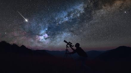Ein Mann betrachtet den Sternenhimmel mit einem Teleskop.