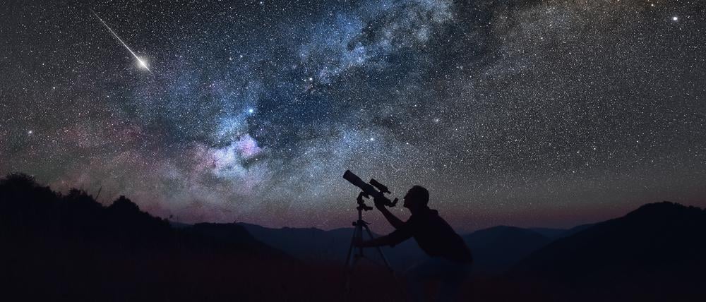 Ein Mann betrachtet den Sternenhimmel mit einem Teleskop.