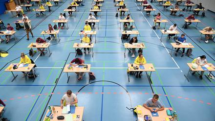 Schülerinnen sitzen während der Deutsch-Abitursprüfung mit dem vorgeschriebenen Abstand zueinander in einer Sporthalle. 
