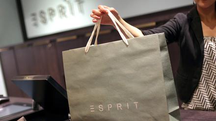 Eine Verkäuferin reicht in einem Esprit-Store in Düsseldorf eine gepackte Einkaufstasche über die Kasse.