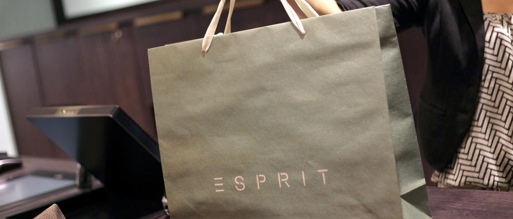 Eine Verkäuferin reicht in einem Esprit-Store in Düsseldorf eine gepackte Einkaufstasche über die Kasse.