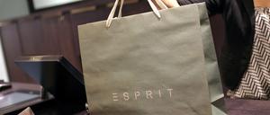 Eine Verkäuferin reicht in einem Esprit-Store in Düsseldorf eine gepackte Einkaufstasche über die Kasse.