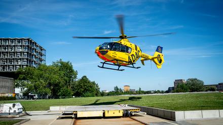 Ein Rettungshelikopter des ADAC befindet sich im Landeanflug über einer Freifläche.