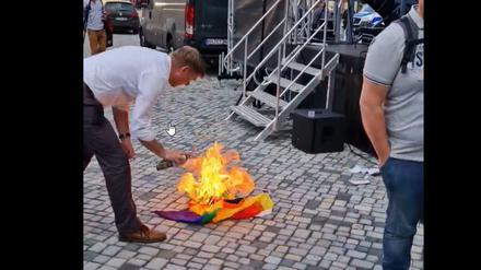 André Poggenburg beim Entzünden der Regenbogenflagge. 