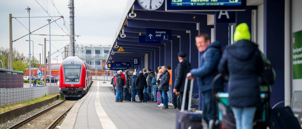 Fahrgäste warten in Norddeich-Mole in Niedersachsen auf einen einfahrenden Regionalzug.