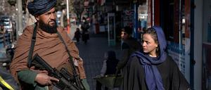 Afghanistan, Kabul: Ein Taliban-Kämpfer steht Wache während eine Frau vorbeiläuft.