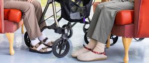 Zwei Bewohner eines Altenheims sitzen neben ihren Rollatoren.