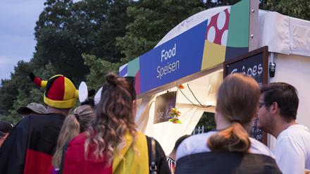 Fans mit Deutschland-Fahnen vor einem der Essen-Stände auf der Fanzone am Brandenburger Tor.
