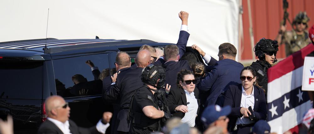 Der republikanische Präsidentschaftsbewerber und ehemalige Präsident Donald Trump bei einer Wahlkampfveranstaltung in Butler von der Bühne in ein Fahrzeug geholfen. Trump wurde bei einem Schusswaffenangriff auf der Bühne am Ohr verletzt. 