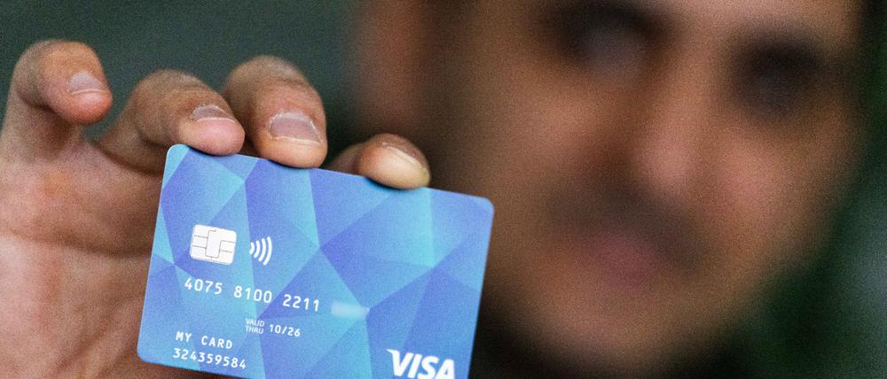 Ein Geflüchteter hält eine Debitcard in der Hand. 