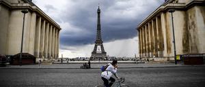 A man rides a bicycle past the Trocadero Esplanade as dark rain clouds loom over The Eiffel Tower in Paris on May 9, 2020, on the 54th day of a lockdown in France aimed at curbing the spread of COVID-19, caused by the novel coronavirus. (Photo by Christophe ARCHAMBAULT / AFP)