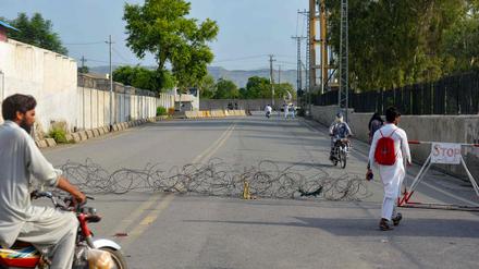 Residents return from a street barbed with wire, a day after an army cantonment was attacked by a militant suicide squad in Bannu on July 16, 2024. 
