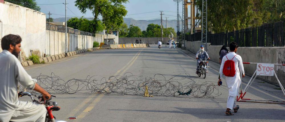 Residents return from a street barbed with wire, a day after an army cantonment was attacked by a militant suicide squad in Bannu on July 16, 2024.