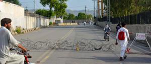 Residents return from a street barbed with wire, a day after an army cantonment was attacked by a militant suicide squad in Bannu on July 16, 2024. 