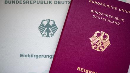 Eine Einbürgerungsurkunde der Bundesrepublik Deutschland (l) und ein deutscher Reisepass liegen auf einem Tisch.