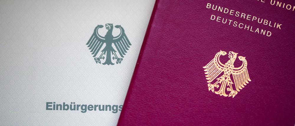Eine Einbürgerungsurkunde der Bundesrepublik Deutschland (l) und ein deutscher Reisepass liegen auf einem Tisch.