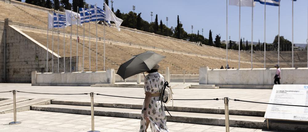 Eine Touristin vor dem Panathinaikos-Stadion in Athen schützt sich mit einem Schirm gegen die Hitze. Die Temperaturen erreichten zwischenzeitlich bis zu 40 Grad.